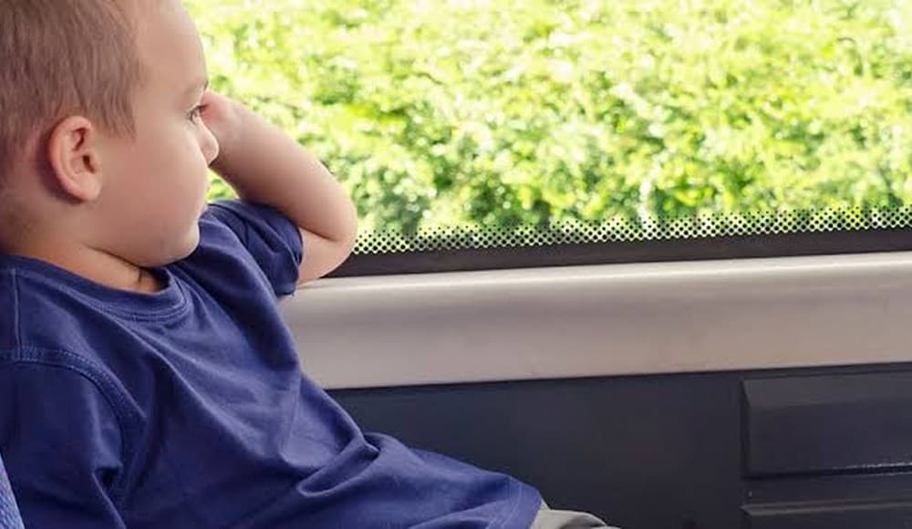 Niño mirando por la ventana durante un trayecto en autobús