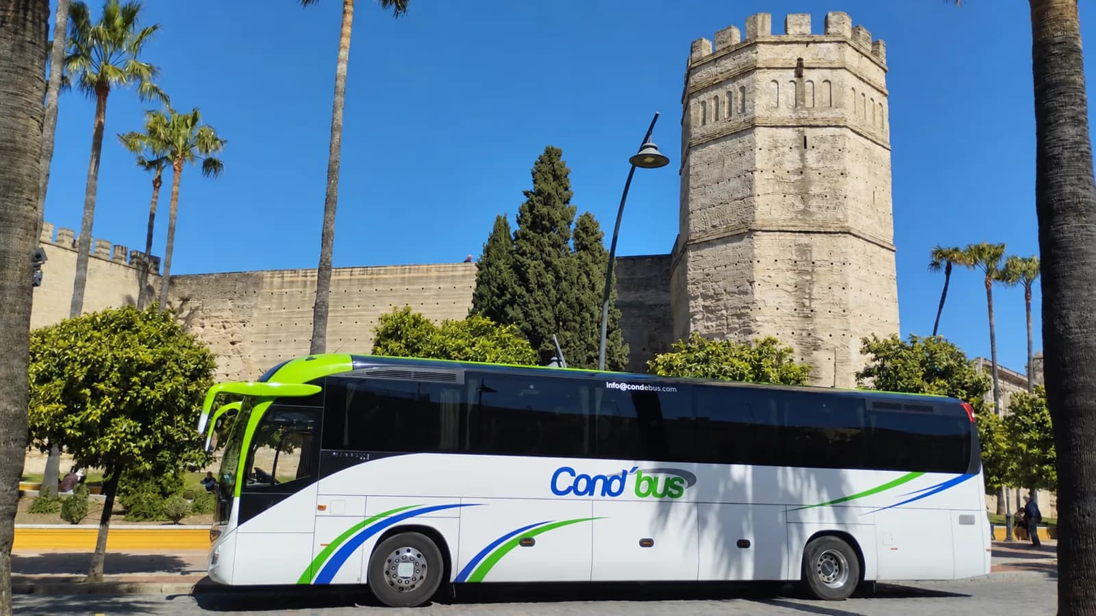 Autocar COND’BUS junto a una fortaleza y palmeras